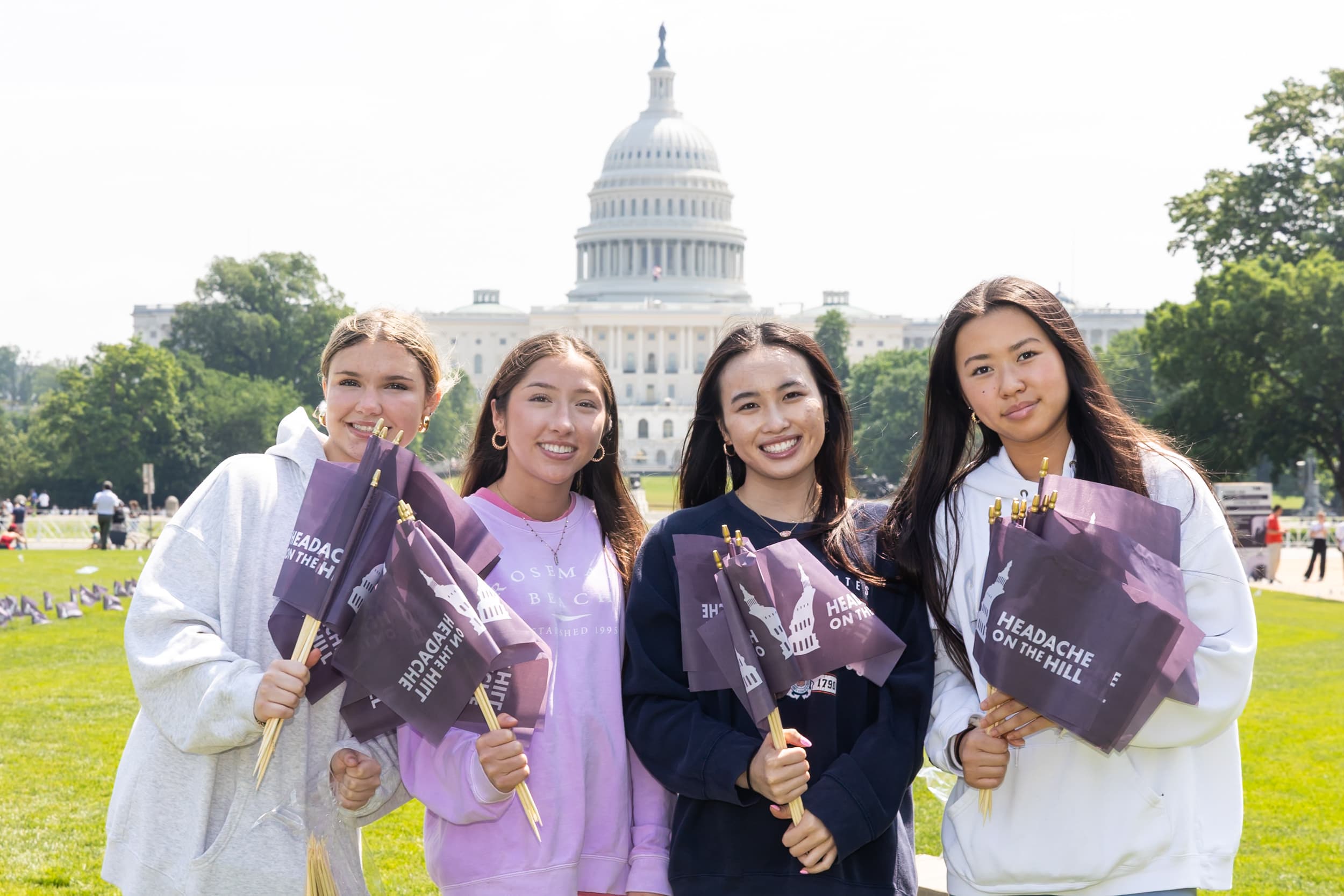 Four women holding Headache on the Hill flags on the National Mall